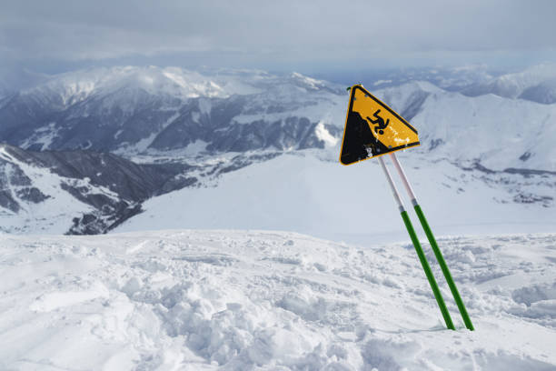 istock label warning of a sharp cliff, standing in  snowy mountains. 956449232