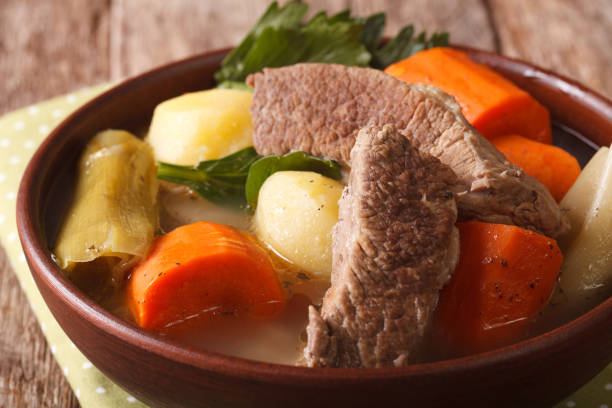 Pot-au-feu beef soup with vegetables in a bowl macro on the table. horizontal
