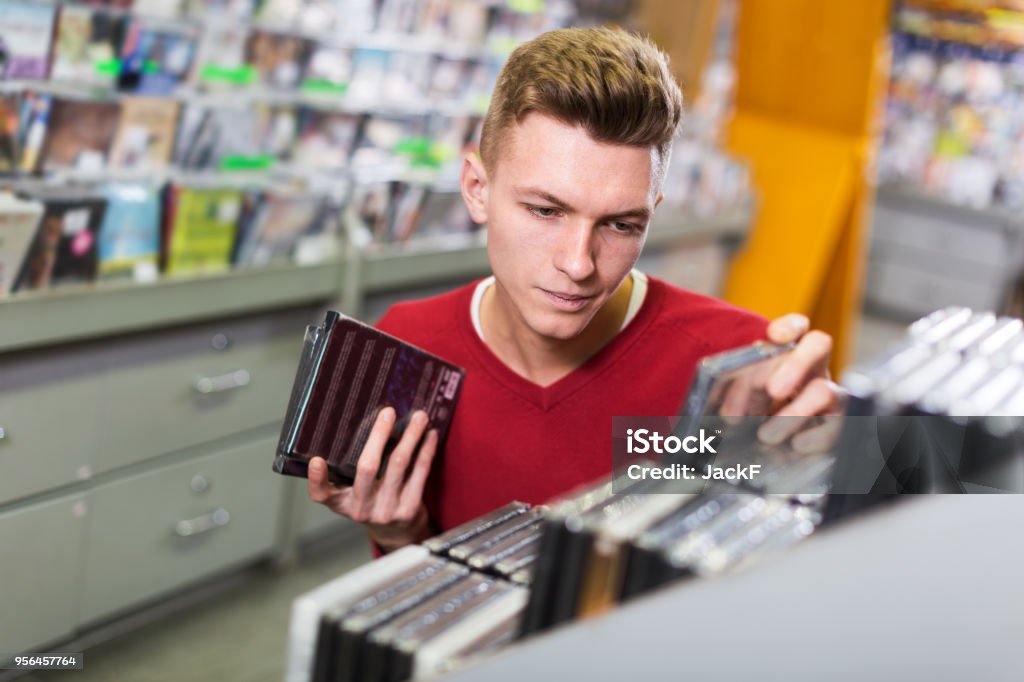 Man choosing DVD in shop Closeup serious young man absorbedly choosing CD and DVD in shop Movie Stock Photo