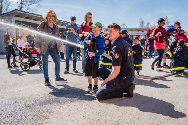 Children and parents at a fire station trying a fire hose. stock photo