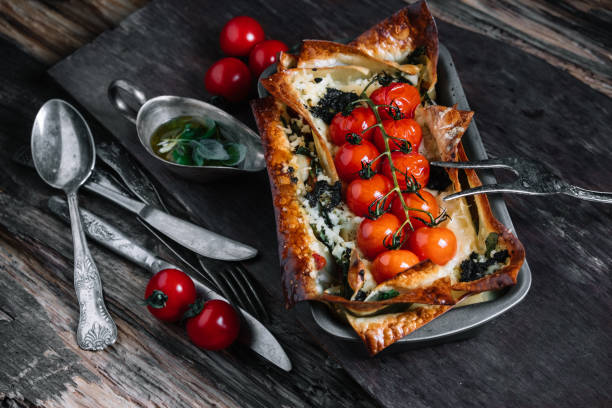 istock Vegetable lasagna with cherry tomatoes in baking dish and ingredients on dark wood background 956461662