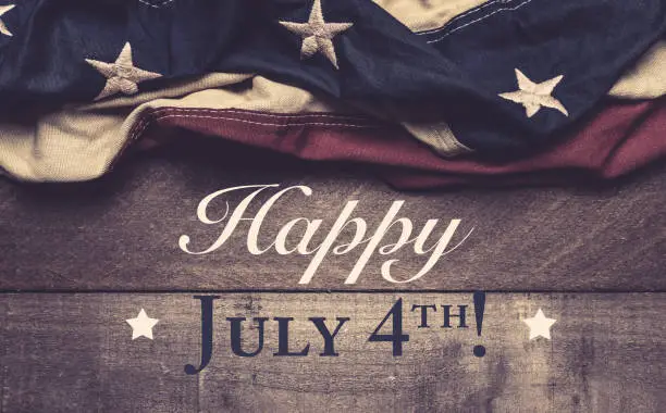 A vintage American flag or bunting on a wooden background with July 4th greeting