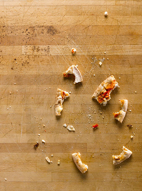 Leftover pizza crumbs scattered on a wooden table