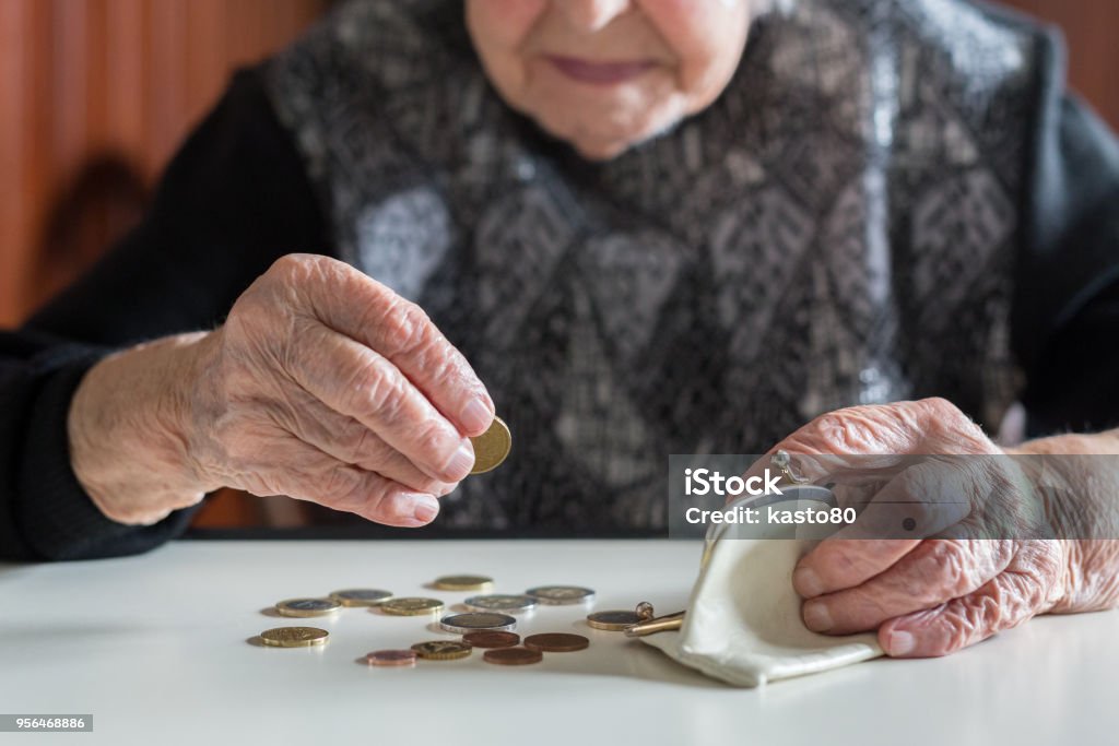 Anziana seduta al tavolo a contare i soldi nel portafoglio. - Foto stock royalty-free di Terza età