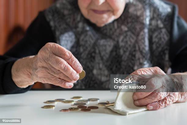 Anziana Seduta Al Tavolo A Contare I Soldi Nel Portafoglio - Fotografie stock e altre immagini di Terza età