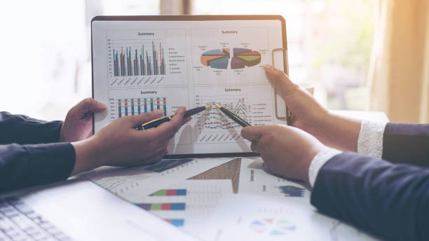 istock financial Image of two  business people pointing at business document presentation summary report , during discussion at meeting , Notebook on wood table 956469912