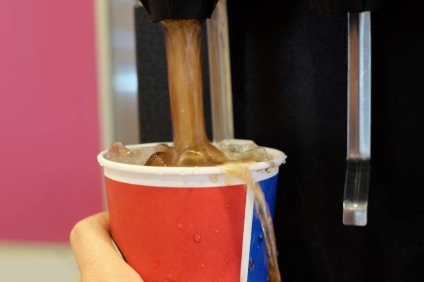 hand hold cool ice soft drink cola in glass and pressing down overflow
