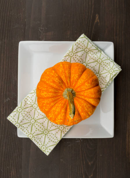istock Bright Orange Pumpkin sits on Square Plate and Napkin 956473514