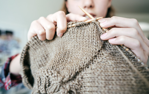 A teenage girl knitting at home.