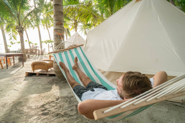 istock Young man relaxing on hammock in glamping campground 956495362