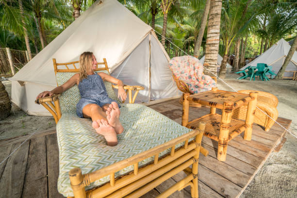Travel woman relaxing in glamping site by the beach in tropical scenery Young woman lying on sofa in front of luxury tent in glamping campsite under the coconut palm trees in the Islands of the Philippines tropical climate people relaxation vacations concept. siquijor island stock pictures, royalty-free photos & images