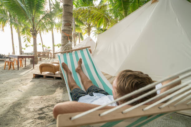 istock Young man relaxing on hammock in glamping campground 956495750
