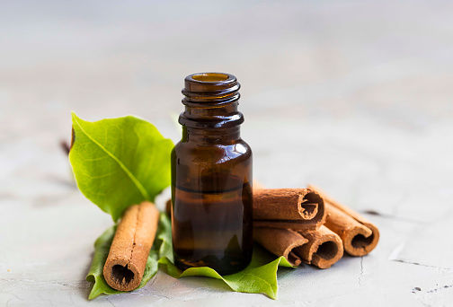 Cinnamon essential oil bottle with cinnamon sticks and leaves, aromatherapy oil