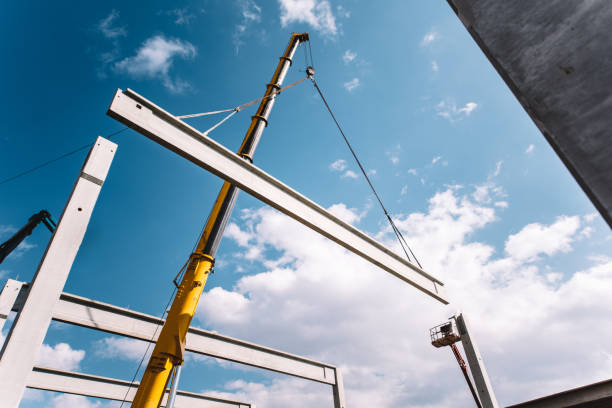 gru industriali che operano e lavorano su cantieri che spostano travi e pilastri di cemento - precast foto e immagini stock