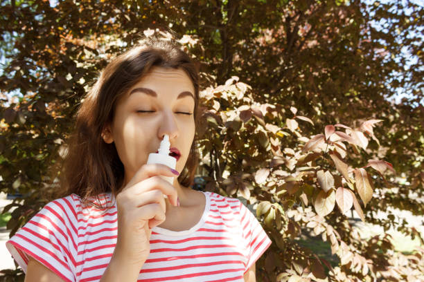 istock Young beautiful woman using nose spray in the park 956513118