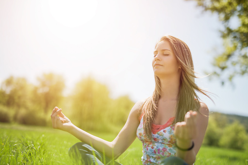 Photo of happy young woman meditating in nature.