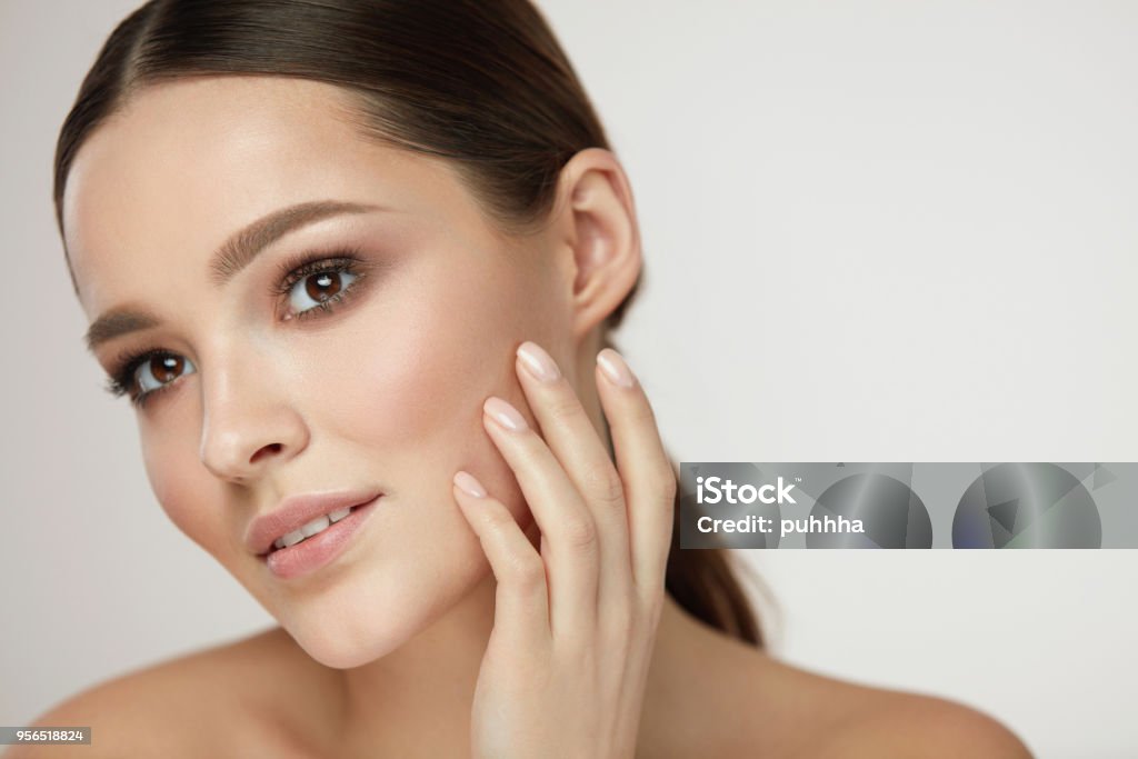 Cosmetic Face Care. Young Woman Caressing Facial Skin Cosmetic Face Care. Portrait Of Beautiful Girl Caressing Facial Skin Posing On Grey Background. Closeup Of Sexy Young Woman With Soft Clean Skin And Natural Makeup. Beauty Concept. High Resolution Human Face Stock Photo