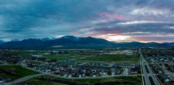 Aerial view at sunrise of Bozeman Montana. Mountain range and city lights in the distance. View looking down Oak St. as the sun comes up.