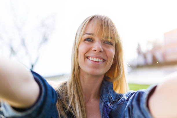 istock Pretty young woman taking a selfie while smiling in the park. 956538528