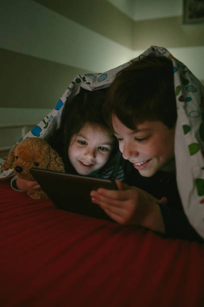 istock Brothers looking at the tablet in the dark 956543298