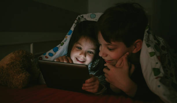 istock Brothers looking at the tablet in the dark 956543512