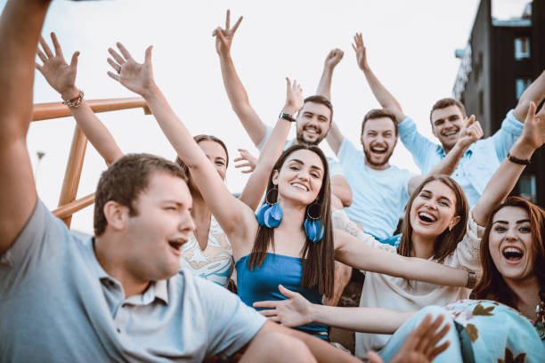istock Group of Young Smiling People with Raised Hands Outdoors 956556020
