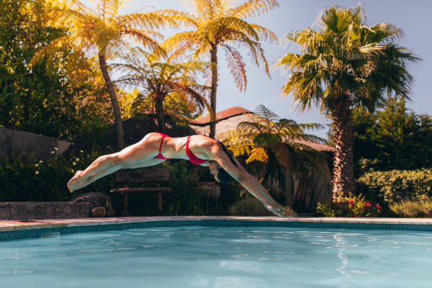istock Woman in bikini diving into swimming pool 956558312