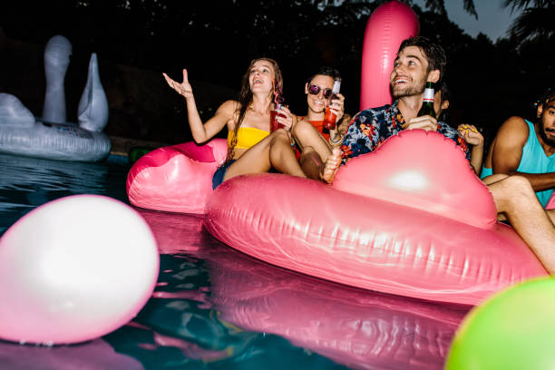 istock Friends enjoying pool party in evening 956558494