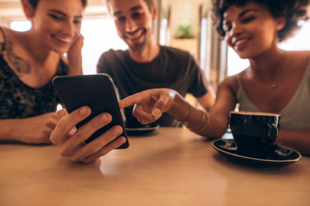 istock Friends looking at smart phone in cafe 956559292