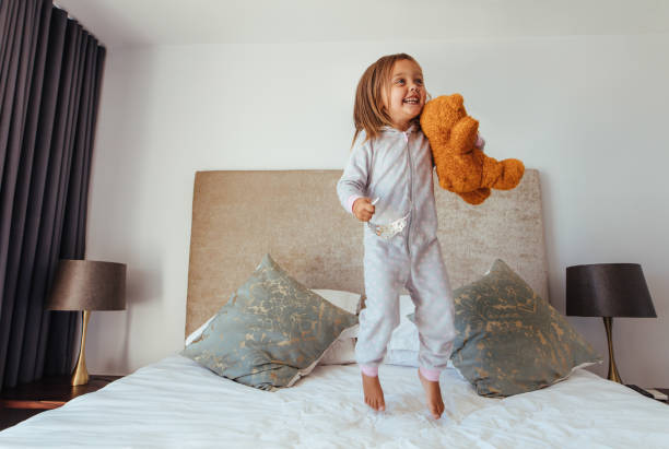bambina che gioca in camera da letto - bed cheerful enjoyment excitement foto e immagini stock