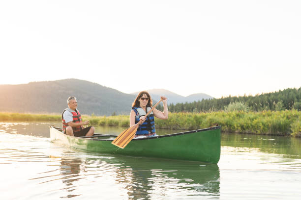istock Senior couple canoeing together around a forested lake. 956560026