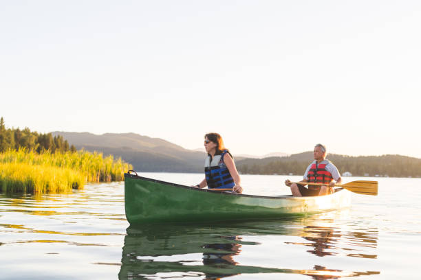 istock Older couple canoe together on a lake at sunset 956560034