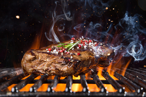 Tasty Beef steak on the grill with fire flames