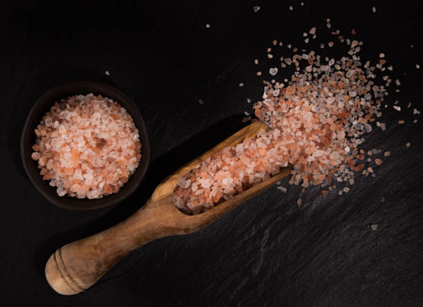 istock Pink Himalayan coarse grain salt on black stone background 956569854