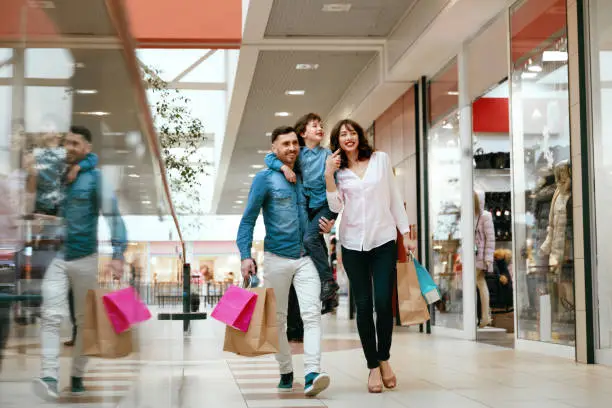 Family Shopping. Happy People With Child Carrying Bags, Walking In Modern Mall. High Resolution.