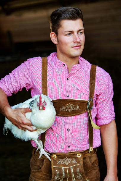 istock young bavarian man holding a white chicken 956580082