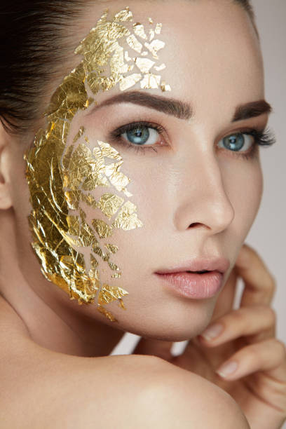 Woman Skin Care. Female With Gold Mask Touching Facial Skin stock photo