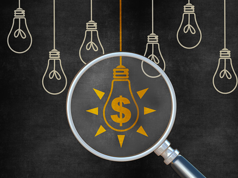 Finance Ideas Concept with Light Bulb on Blackboard