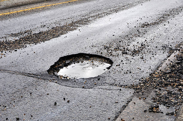 istock A large pot hole filled with water on an asphalt road 95658927