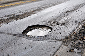 A large pot hole filled with water on an asphalt road