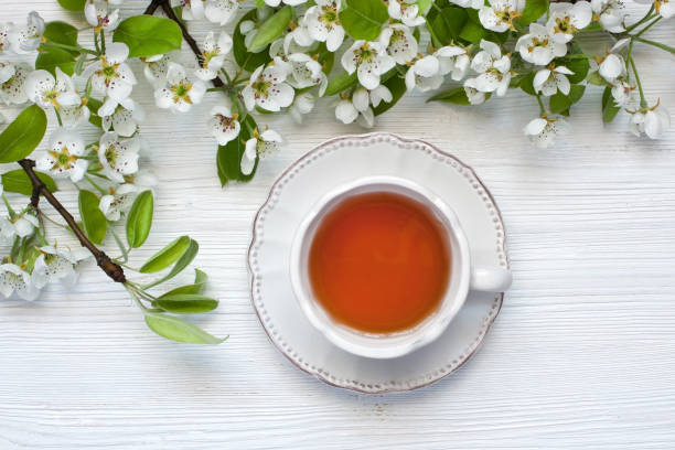 istock Tea mug and pear flowers on wooden background. Top view 956597532