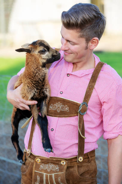 istock blond bavarian man holding a little goat 956600614