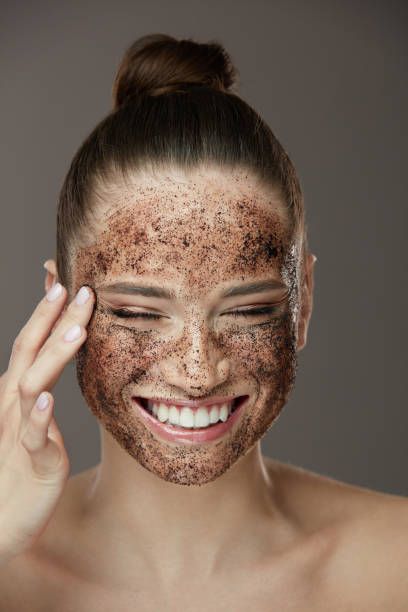 Face Skin Scrub. Smiling Girl Applying Coffee Mask Scrub On Skin stock photo