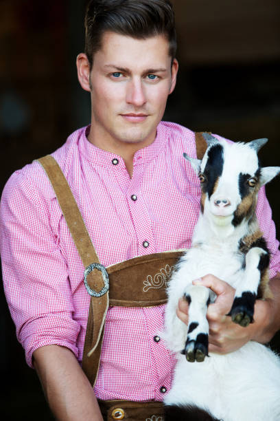 istock young bavarian man holding a goat 956601686