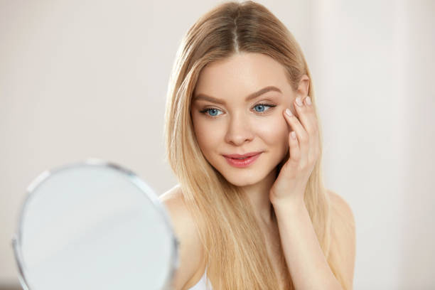 istock Makeup And Beauty. Female Touching Face Skin Looking In Mirror 956605680