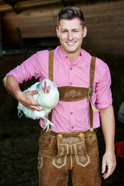 portrait of young bavarian man holding a white chicken