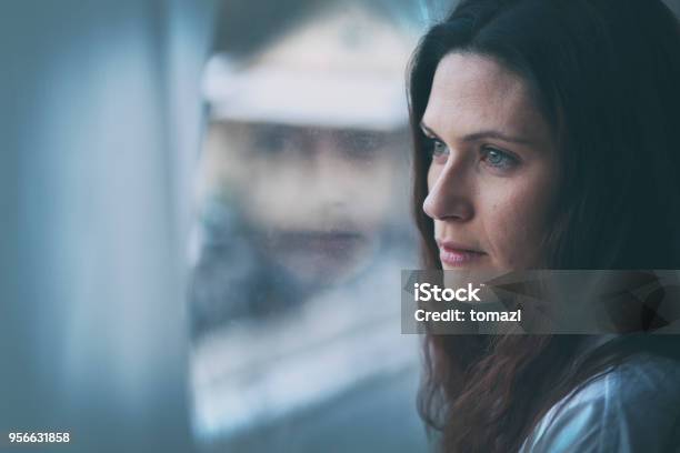 Young Woman Looking Through Window With Reflection Stock Photo - Download Image Now - Women, One Woman Only, Sadness