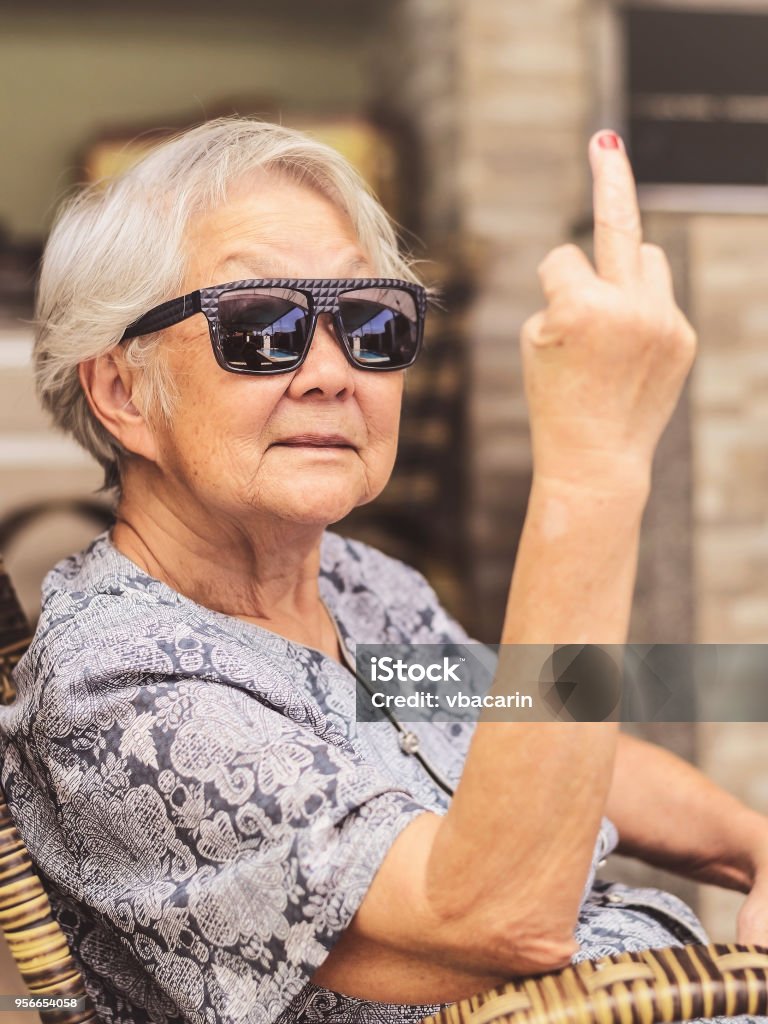 Fresca viejo señora, usar gafas de sol, expresando a sí misma mostrando el dedo medio. - Foto de stock de Tercera edad libre de derechos