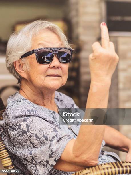 Cool Old Lady Wearing Sunglasses Expressing Herself Showing The Middle Finger Stock Photo - Download Image Now