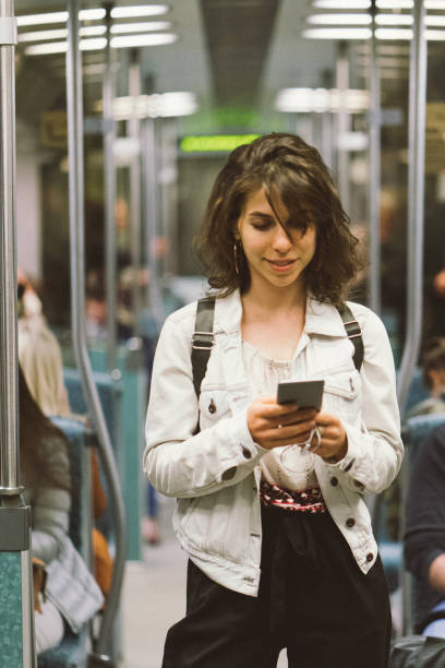istock Young woman using smartphone on the subway train 956662840
